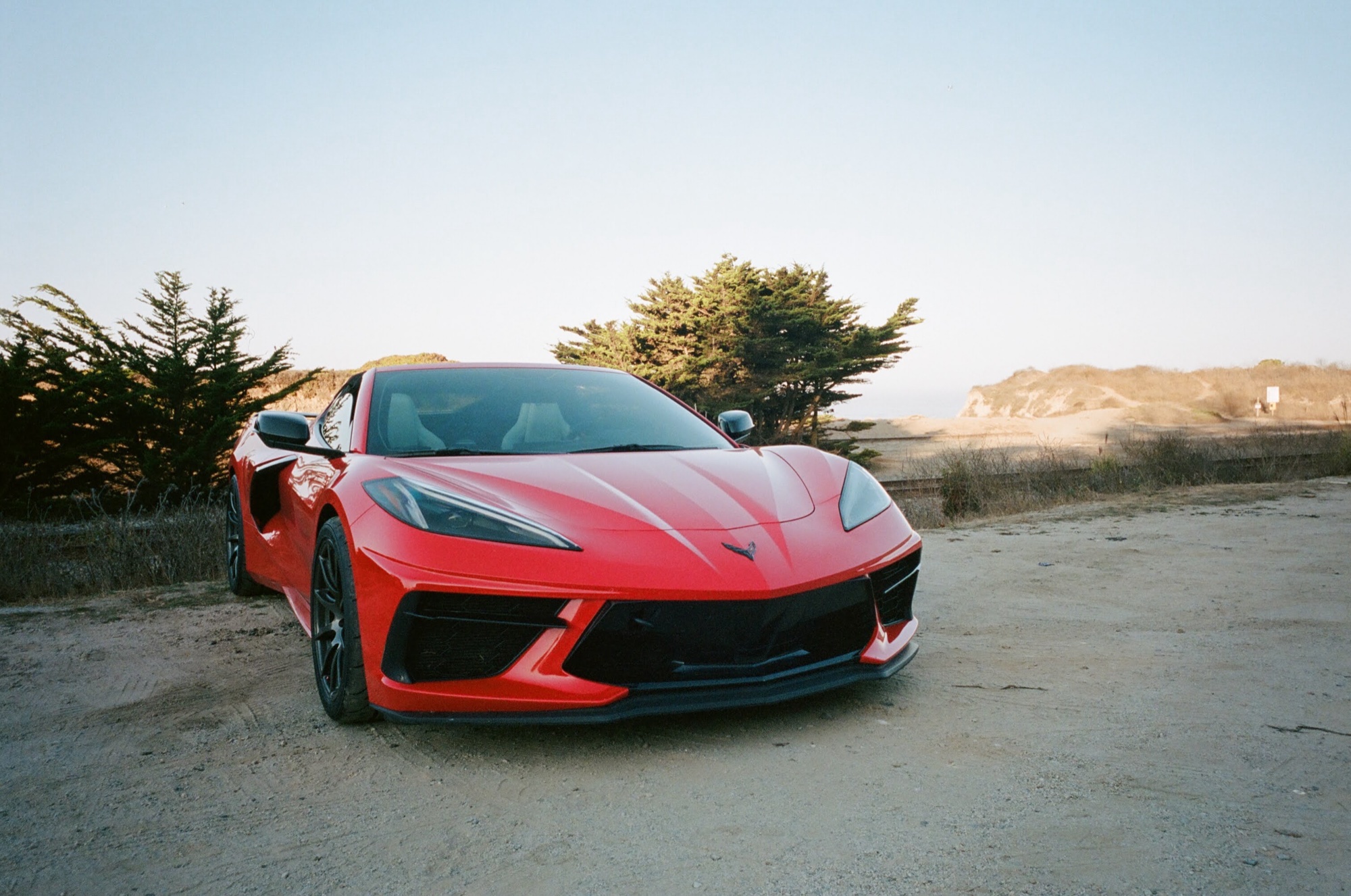 Red C8 Corvette parked by the dunes at golden hour, shot on film